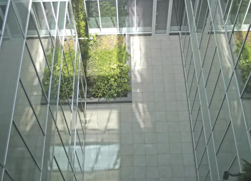 Patio interior acristalado con pavimento claro y jardín vertical