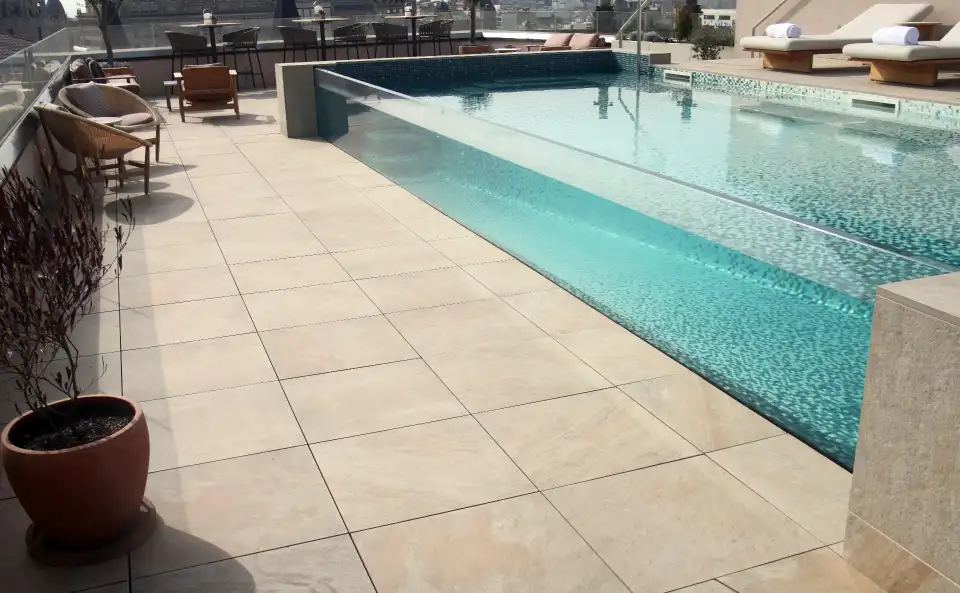 Hotel pool with light stone flooring on the terrace