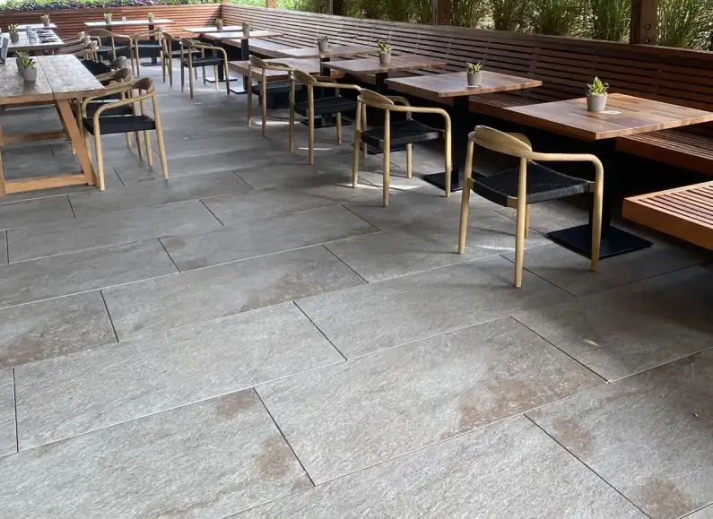 Terraza de restaurante con mesas de madera sobre pavimento gris