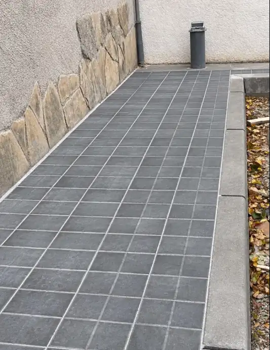 Pasillo exterior con pavimento Silent12SC® gris oscuro junto a una jardinera