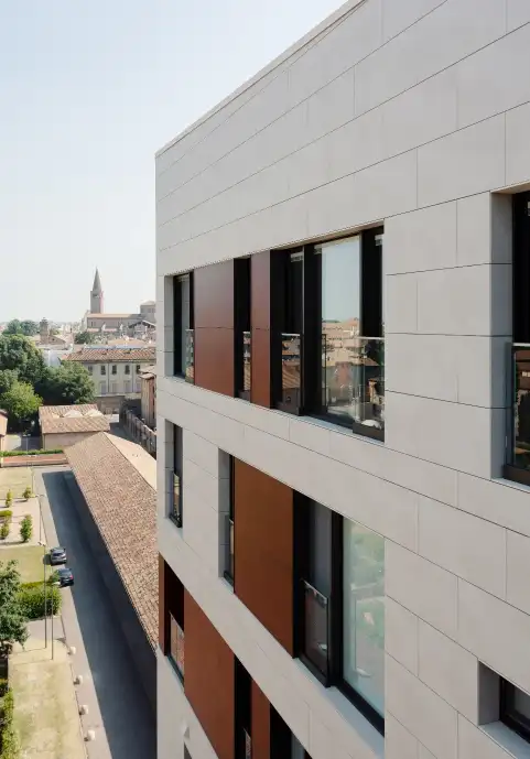 Esquina de un edificio con fachada BioStone20 SNS® clara y vistas a la ciudad