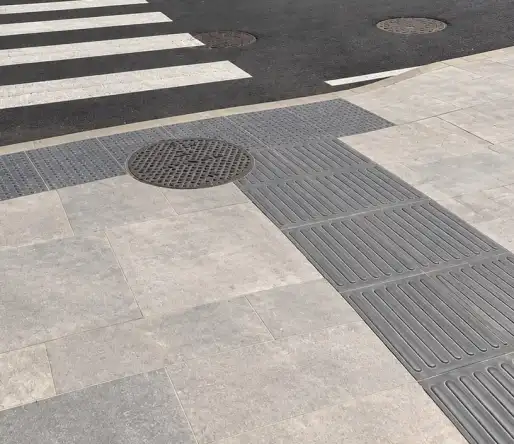 Pedestrian crossing with Tactile15® guidance tiles next to a manhole cover