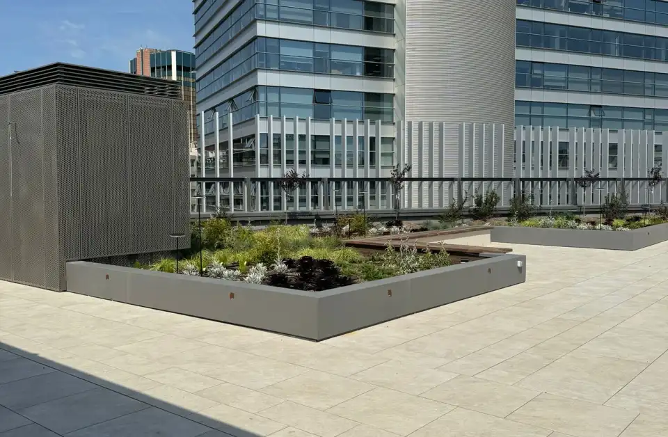 Terraza ajardinada del Edifici Aura con pavimento claro de gran formato y jardineras