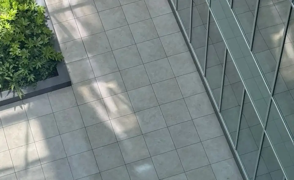 Terraza con pavimento de baldosas grises junto a una fachada de vidrio