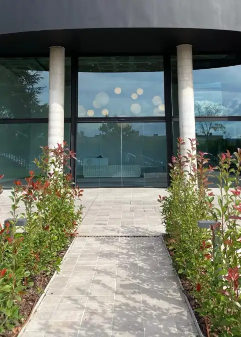 Acceso a edificio de oficinas con pavimento de piedra entre jardineras