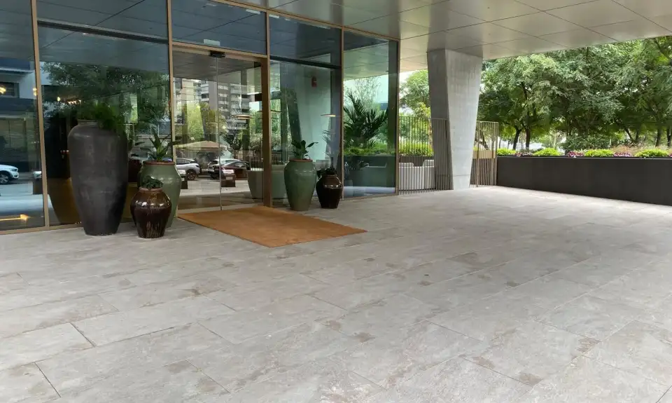 Porche de entrada con pavimento de piedra y grandes macetas
