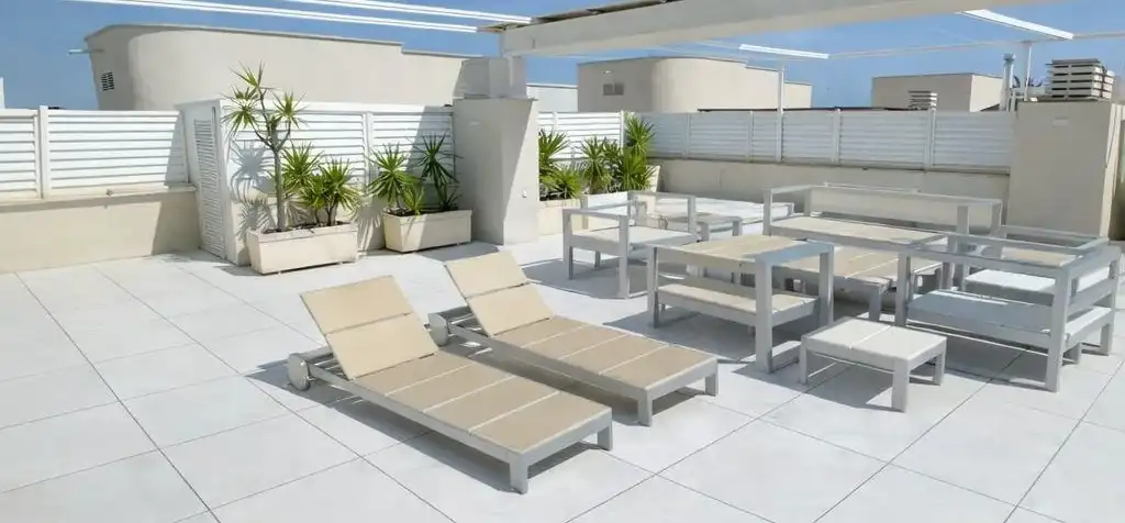 Terraza en cubierta con tumbonas y mobiliario de exterior sobre pavimento claro de gran formato