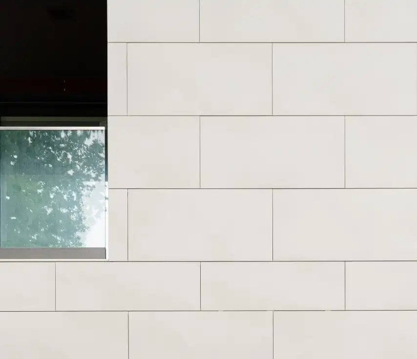 Fachada revestida con placas BioStone20 SNS® claras junto a una ventana